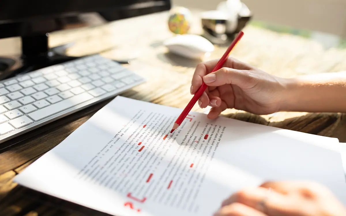 Woman copyediting a paper with a red pencil